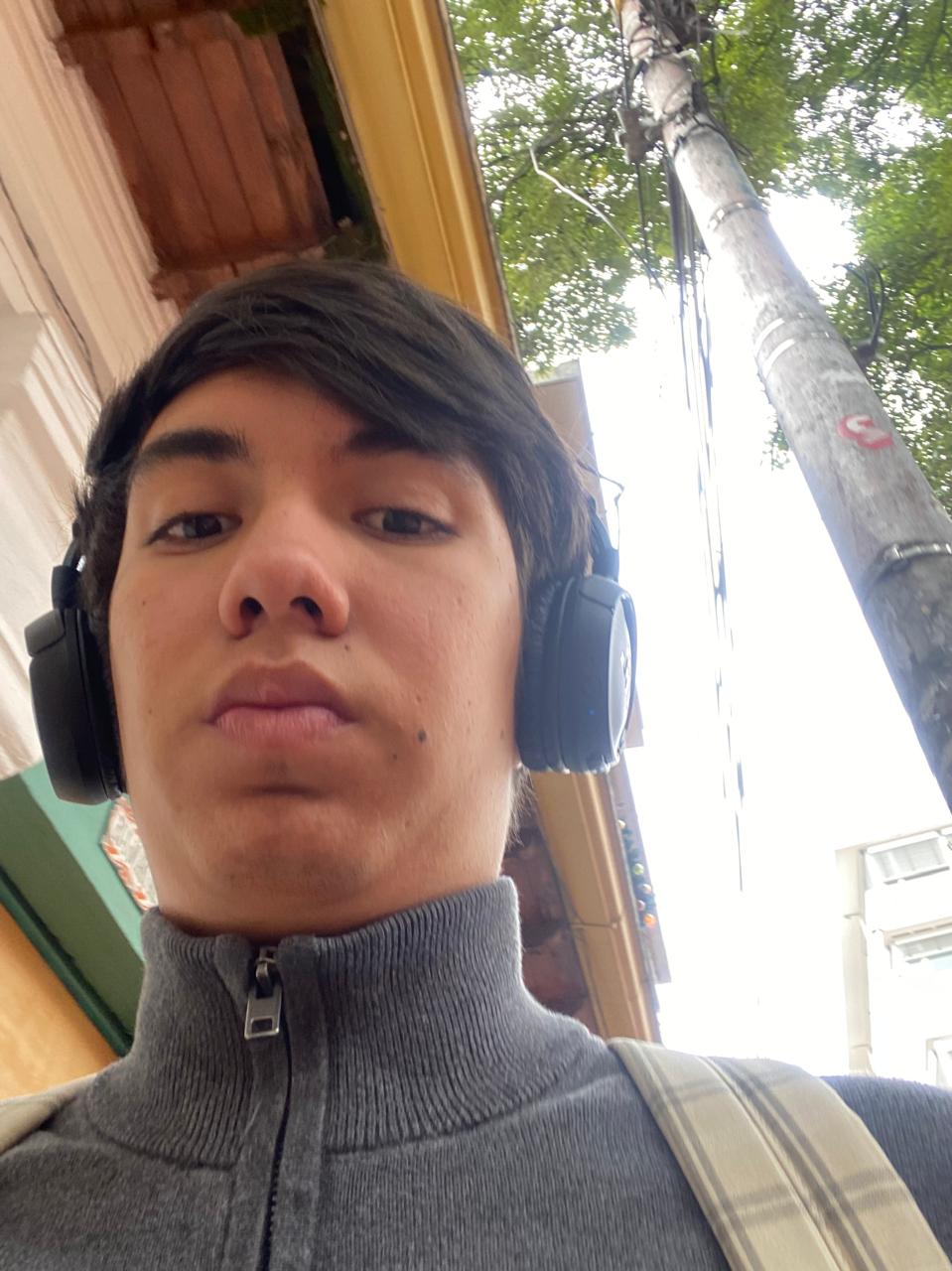 Kevin con audífonos y morral, llegando a la universidad
